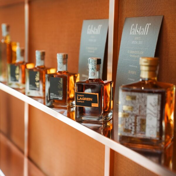 Row of Grappa Lagrein bottles on a shelf alongside Falstaff spirits awards for St. Urban Distillery.