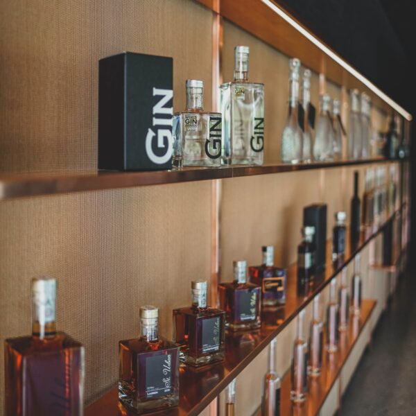 Shelves displaying gin and other liquor bottles with golden labels and different shapes and sizes.