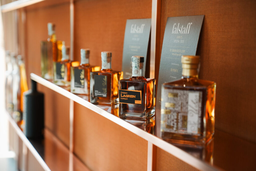 Bottles of Falstaff Grappa Lagrein and St. Urban Distillery spirits lined up on a shelf with rating cards.