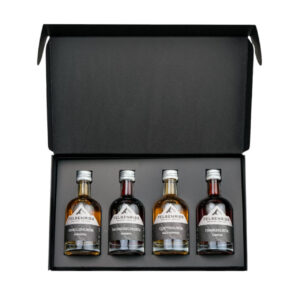 Open gift box containing four small bottles of Felsenriss liqueur in different fruit flavors, lined up inside.