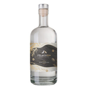 A clear glass bottle of Felsengin Brennerei Distillery batch-distilled gin with a gray, gold, and white label.