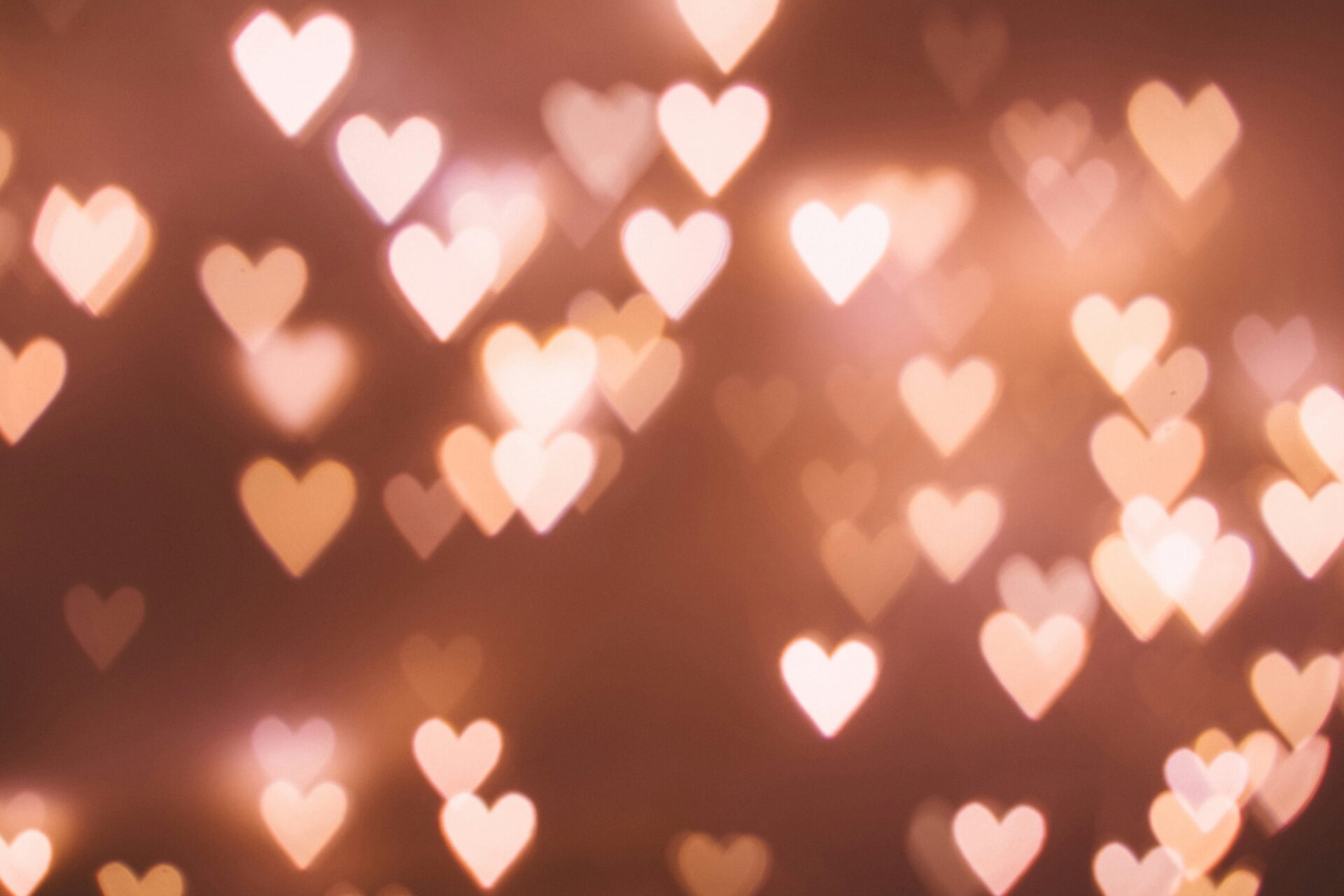 Out-of-focus lights shaped like hearts glow against a blurred brownish background.